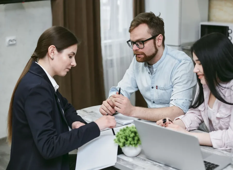 Mains examinant des documents d'assurance emprunteur et des devis comparatifs sur un bureau