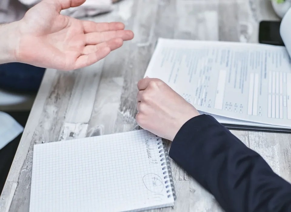 Main d'une personne consultant des devis d'assurance habitation sur une tablette entourée de documents