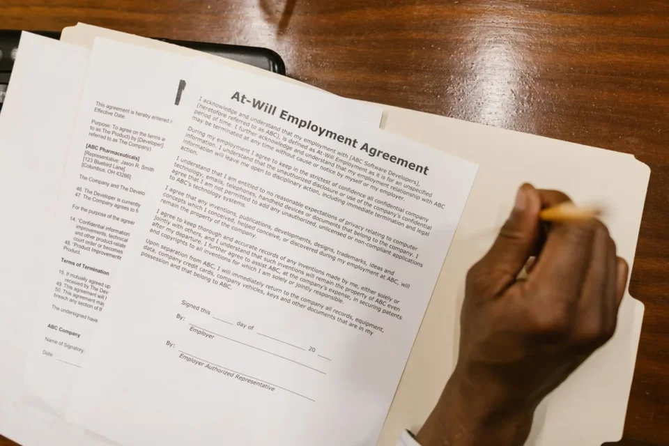 Deux mains signant un contrat de travail sur un bureau avec stylo et documents