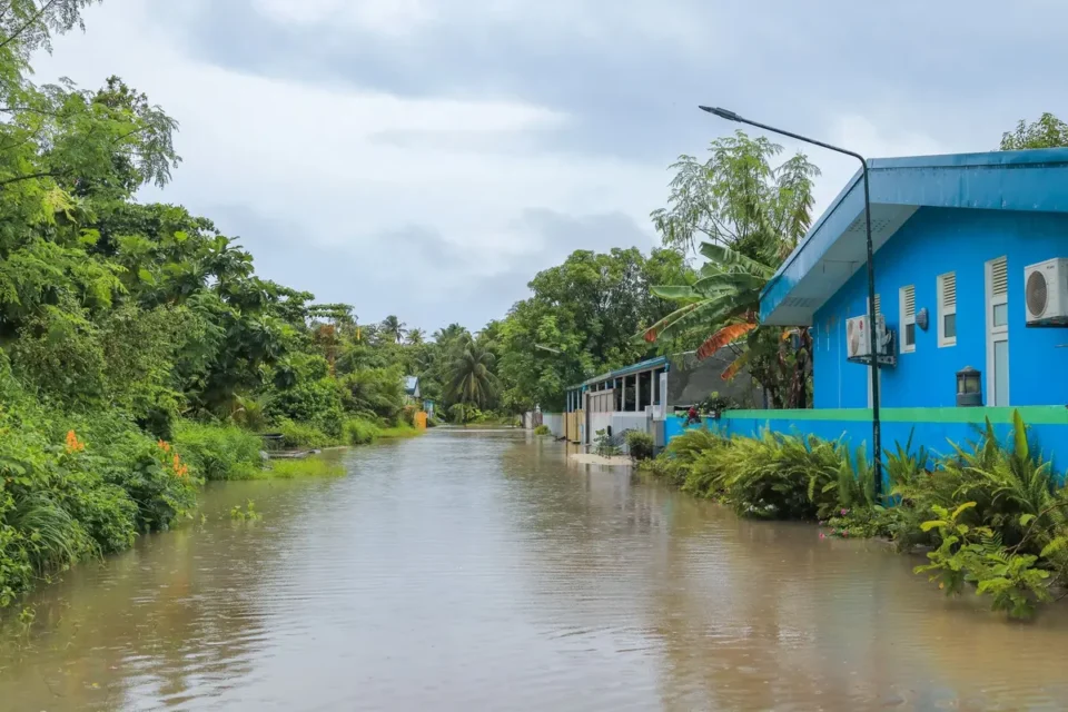 Maison inondée avec l'eau montant contre les murs et des sacs de sable protégeant l'entrée