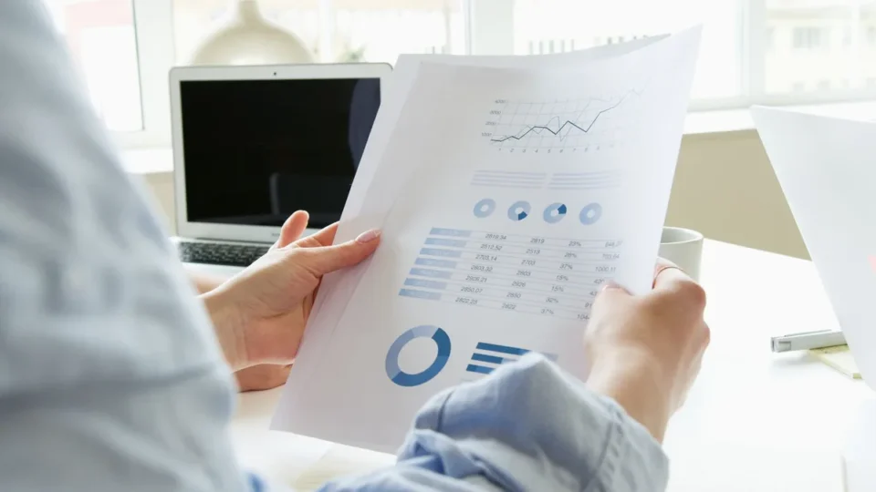 Investisseur examinant des graphiques boursiers et des documents financiers sur son bureau.