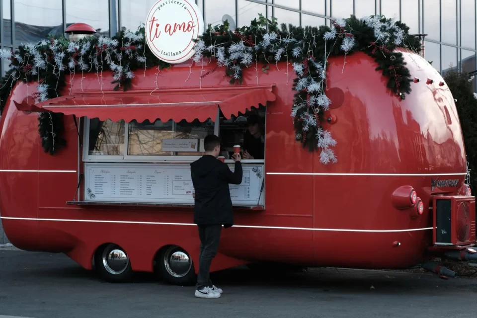 File de clients devant un food truck en zone urbaine, préparation visible à travers la fenêtre de service