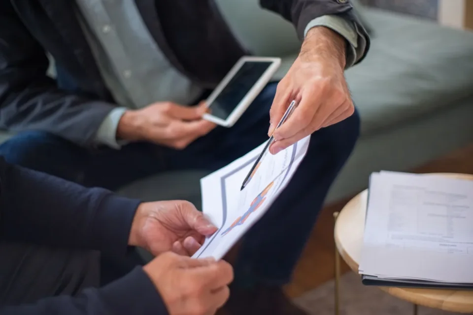 Client examinant des documents d'assurance avec des contrats étalés sur un bureau