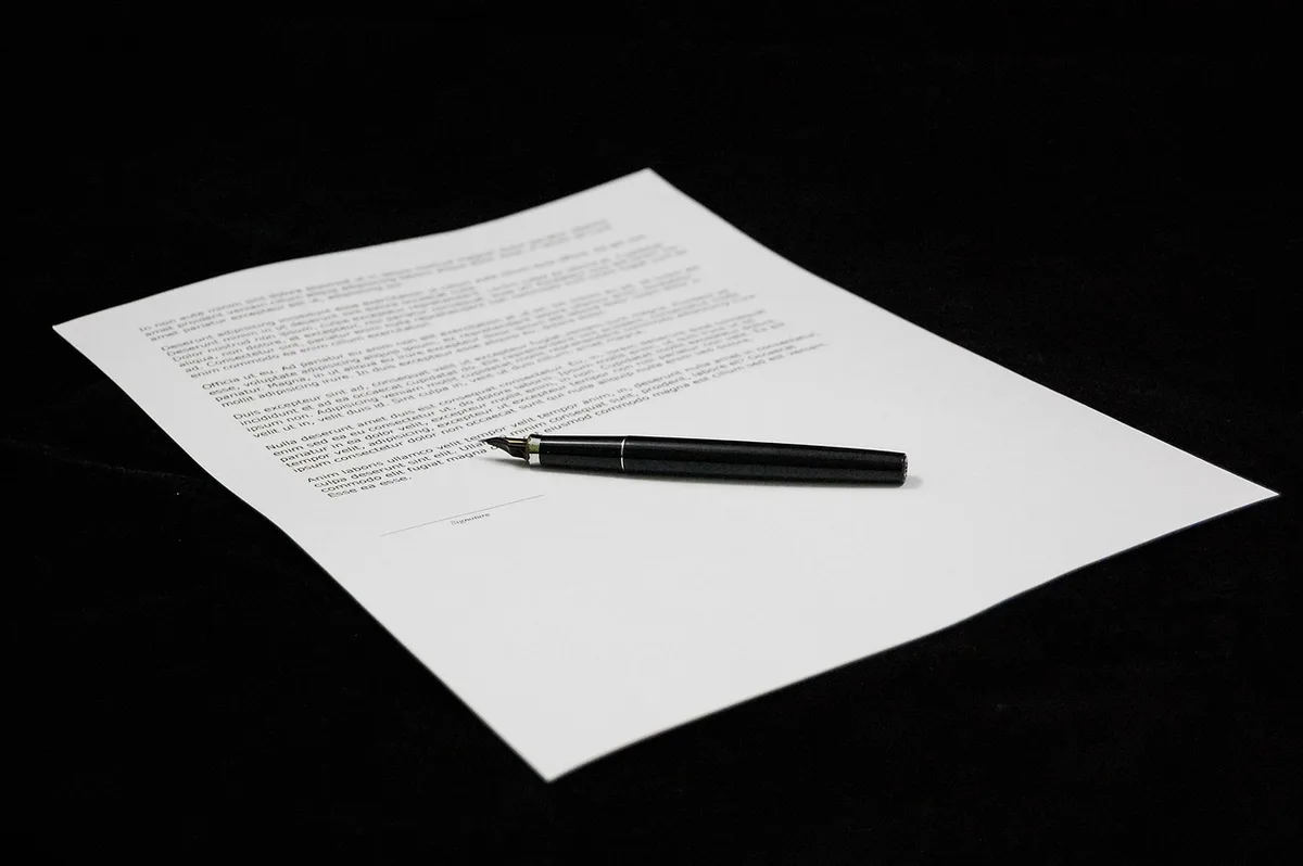 Deux mains signant un accord chez le notaire, bureau lumineux