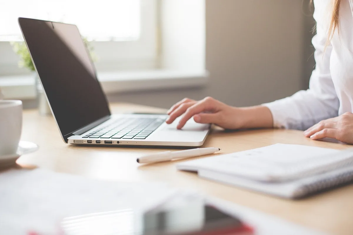Mains d'un salarié remettant un formulaire de transfert de jours sur un bureau