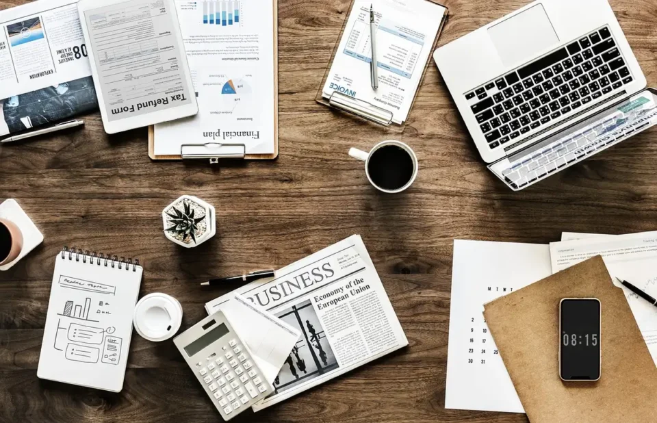 Cahier de recettes, calculatrice et factures triées sur une table de bureau