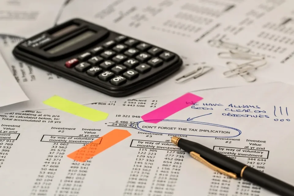 Personne consultant des documents d'assurance et relevés bancaires sur un bureau, expression préoccupée