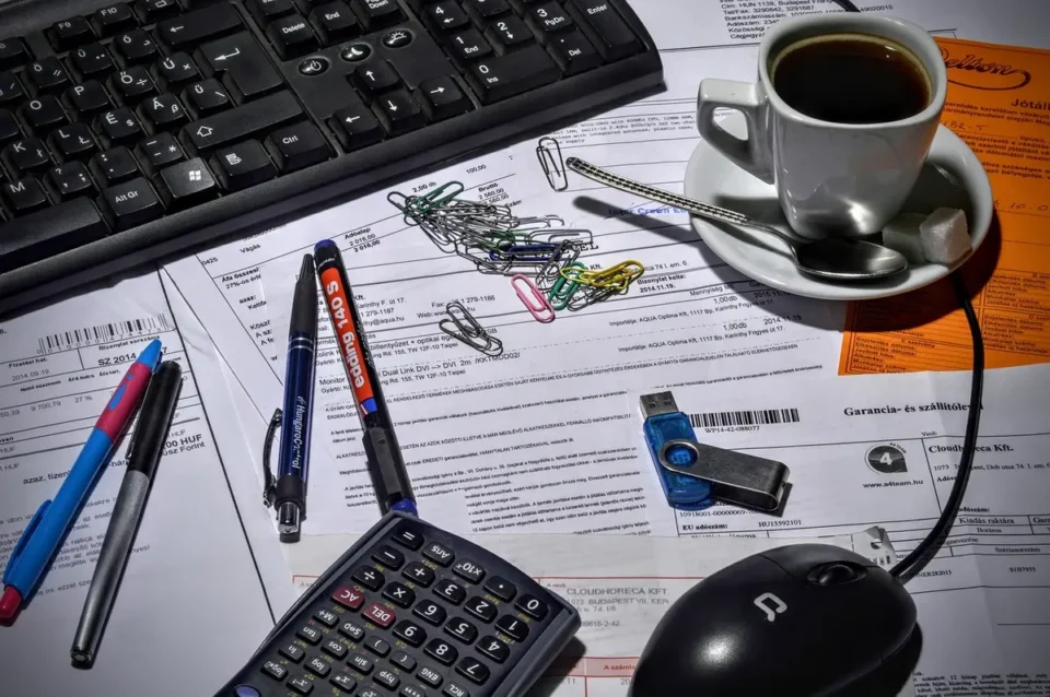 Personnes anonymes remplissant des documents de prêt sur un bureau lumineux avec une calculatrice floue