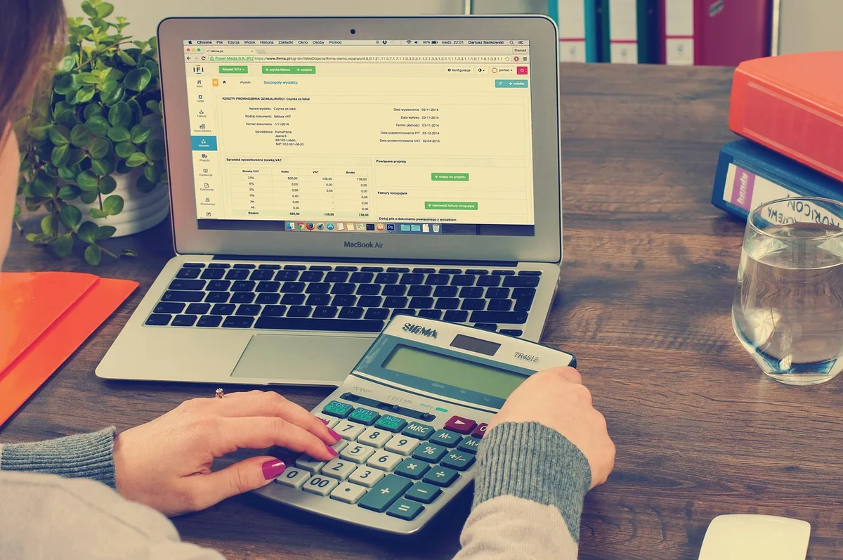 Main posée sur des justificatifs et une calculatrice près d’une fenêtre
