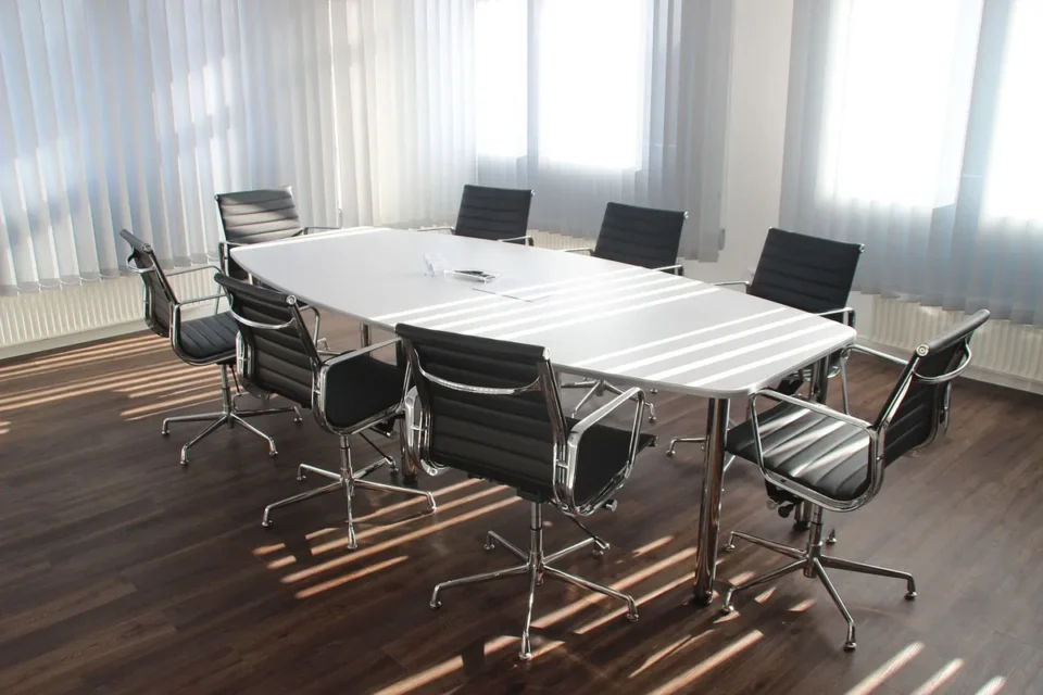 Table de réunion en journée, mains anonymes feuilletant des statuts et documents juridiques
