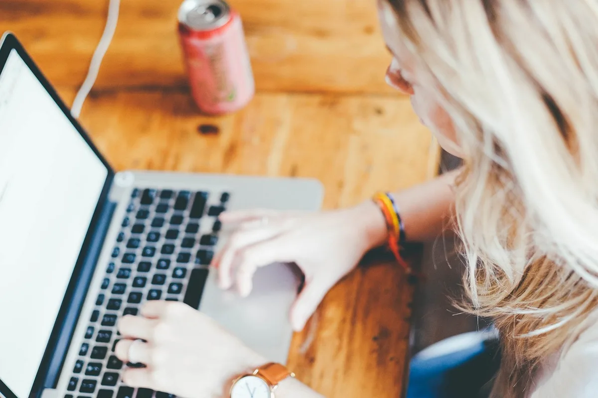 Personne en télétravail avec ordinateur portable et planning visible à la fenêtre