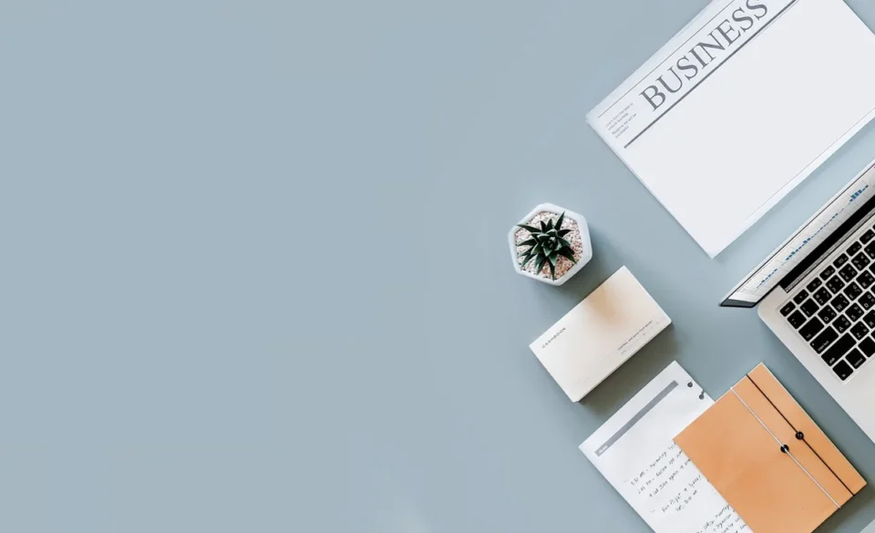 Bureau en journée avec ordinateur, documents et mains comparant des notes
