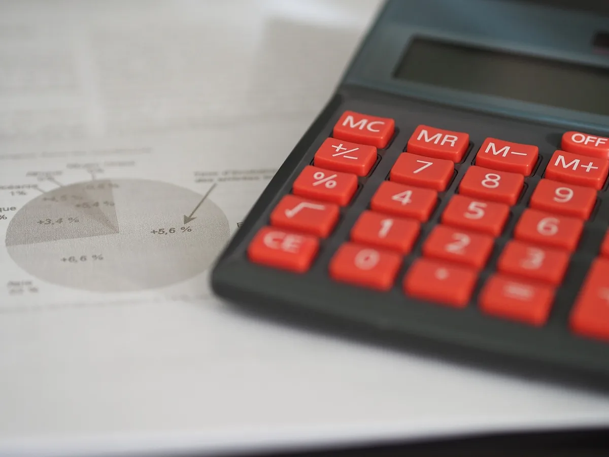 Calculatrice et papiers de charges sur un bureau pour estimer le coût d'un cabinet