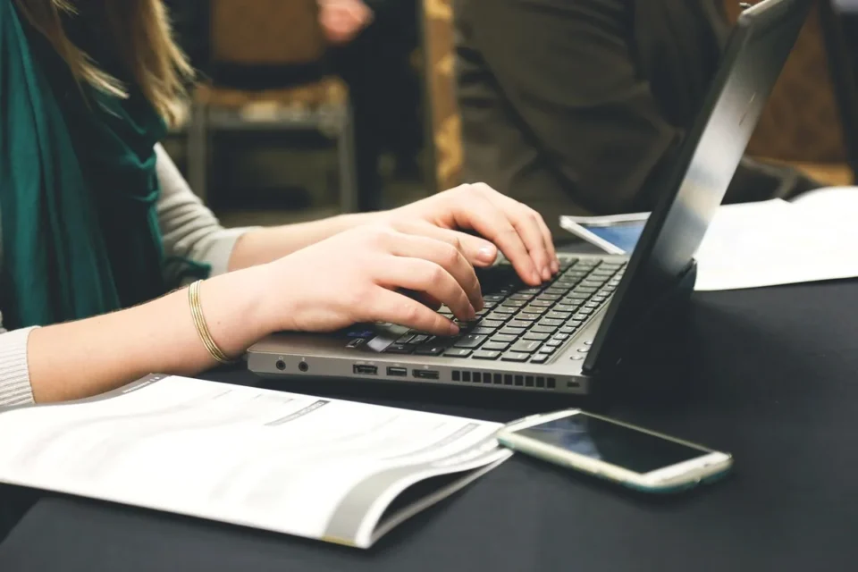 Coin de bureau en journée avec carnet, documents et mains anonymes lors d'un entretien