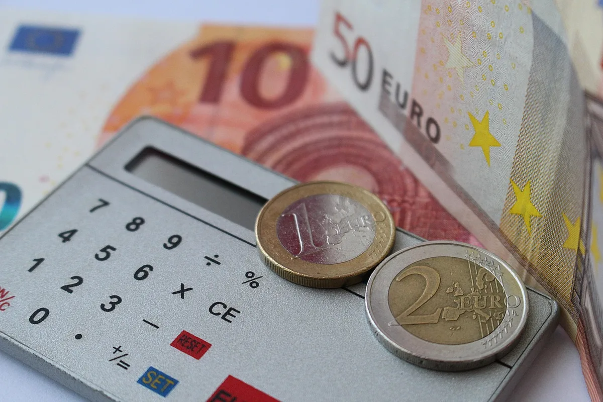Table de travail montrant calculs et documents financiers pour évaluer coût global