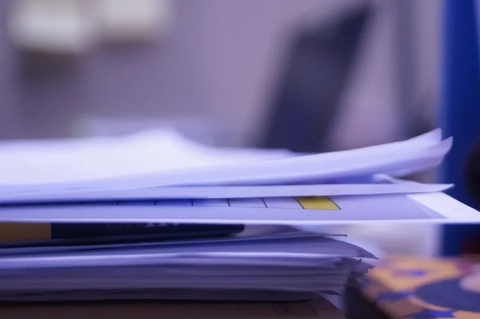 Bureau lumineux avec papiers administratifs et mains préparant un dossier de titre de séjour